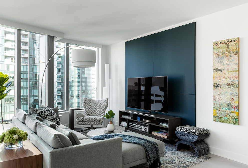 This is an example of a contemporary living room in San Francisco with white walls, a freestanding tv and grey floor.