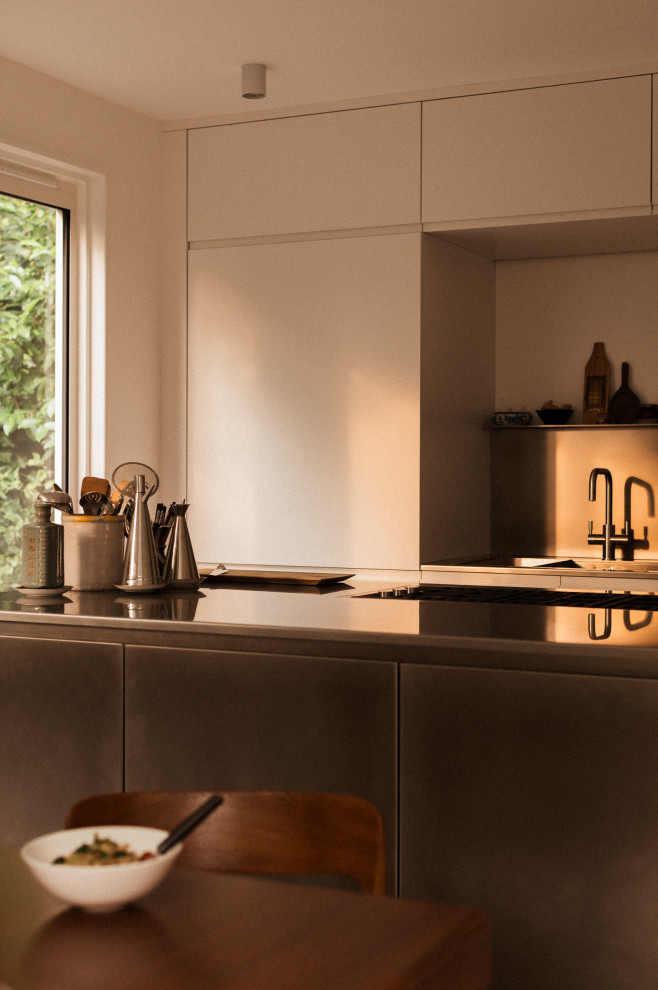 Esempio di una cucina contemporanea di medie dimensioni con lavello integrato, ante lisce, ante in acciaio inossidabile, top in acciaio inossidabile, elettrodomestici da incasso e pavimento in cemento