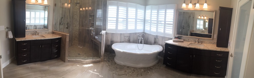 Freestanding bathtub - large transitional master gray tile and porcelain tile light wood floor and brown floor freestanding bathtub idea in Baltimore with shaker cabinets, dark wood cabinets, a two-piece toilet, beige walls, an undermount sink, solid surface countertops and a hinged shower door