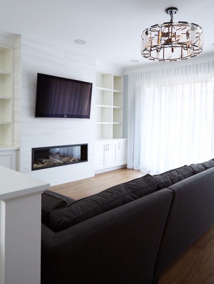 Design ideas for a large transitional open concept living room in Toronto with white walls, medium hardwood floors, a standard fireplace, a tile fireplace surround and a wall-mounted tv.