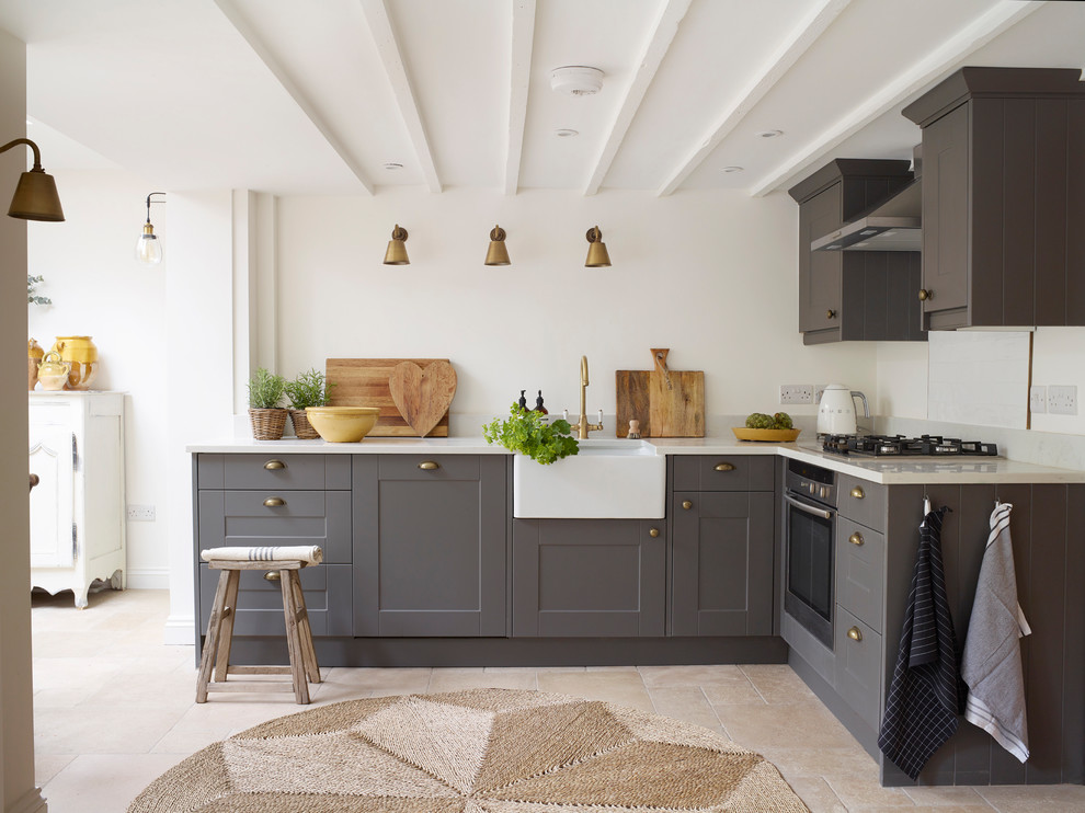 Design ideas for a country l-shaped kitchen in Oxfordshire with a farmhouse sink, shaker cabinets, grey cabinets, quartzite benchtops, stainless steel appliances, limestone floors, no island, white benchtop and beige floor.
