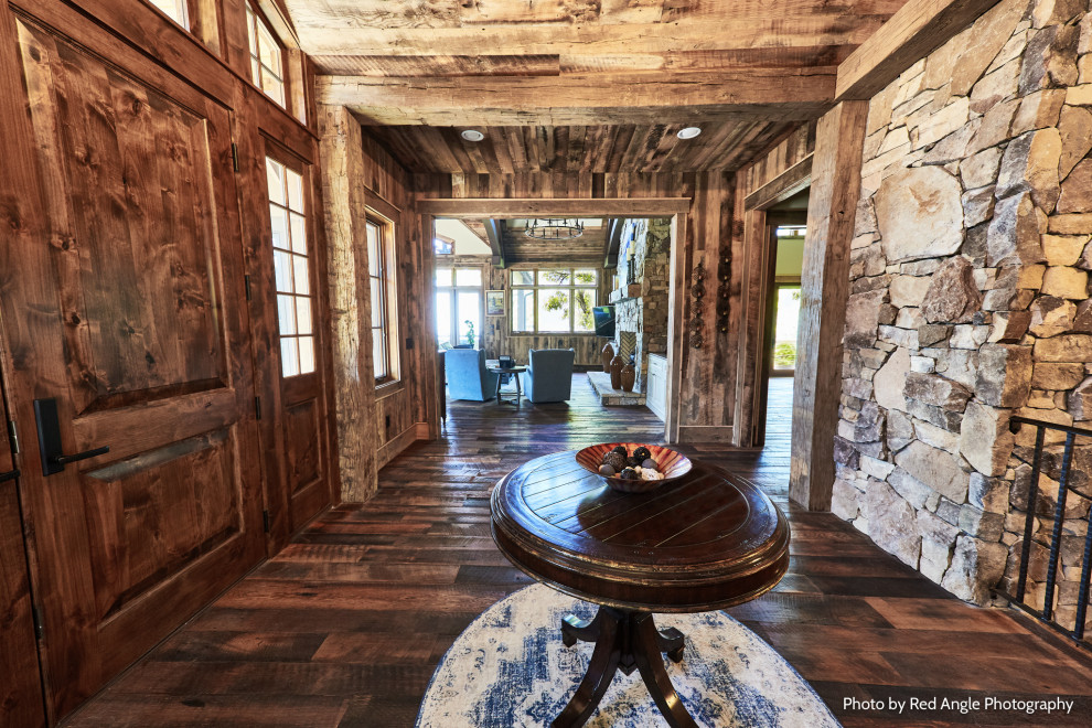 Mid-sized mountain style dark wood floor, brown floor, exposed beam and wood wall foyer photo with a dark wood front door