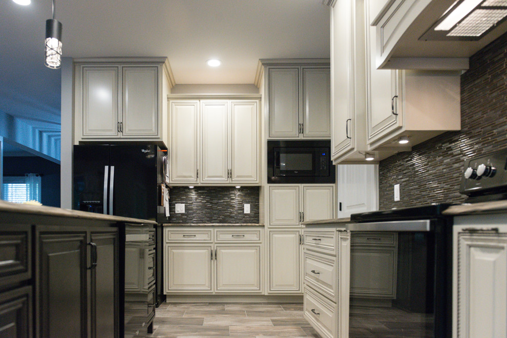 Inspiration for a large transitional l-shaped ceramic tile eat-in kitchen remodel in Chicago with an undermount sink, raised-panel cabinets, dark wood cabinets, marble countertops, brown backsplash, glass tile backsplash, black appliances and an island