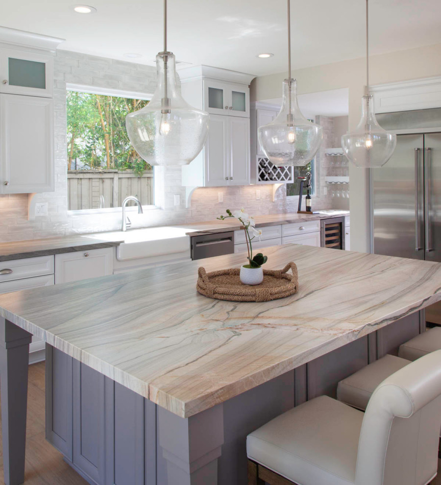 Photo of a mid-sized beach style galley eat-in kitchen in San Diego with an undermount sink, shaker cabinets, white cabinets, quartzite benchtops, white splashback, glass tile splashback, stainless steel appliances, laminate floors, with island, brown floor and multi-coloured benchtop.