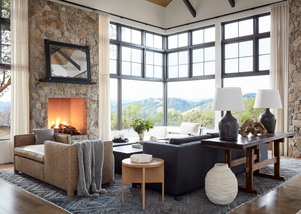 Design ideas for a country open concept living room in San Francisco with white walls, medium hardwood floors, a standard fireplace, a stone fireplace surround and brown floor.