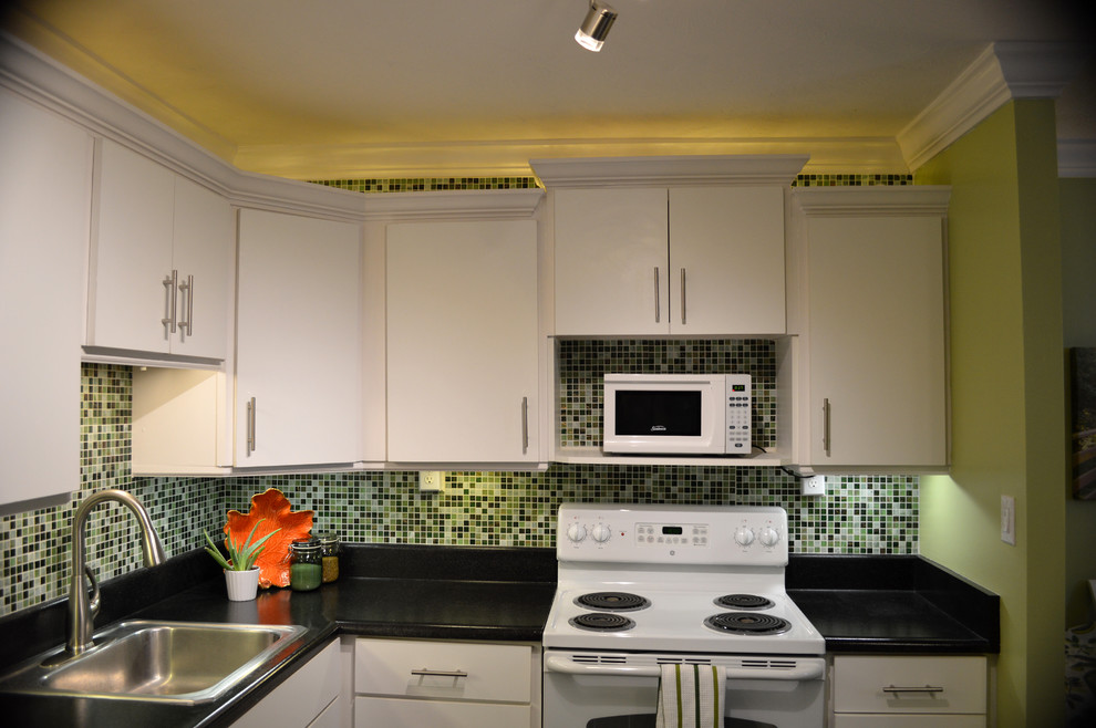 Photo of a small asian l-shaped open plan kitchen in Salt Lake City with a drop-in sink, flat-panel cabinets, white cabinets, laminate benchtops, green splashback, glass tile splashback, white appliances, vinyl floors and with island.