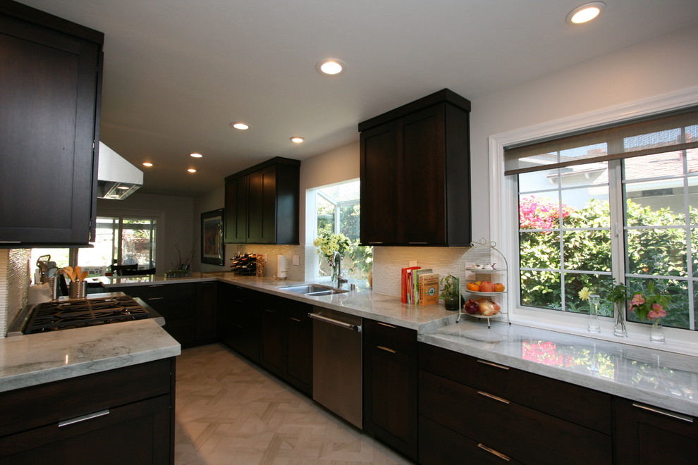 Example of a mid-sized transitional l-shaped porcelain tile kitchen design in Orange County with a double-bowl sink, recessed-panel cabinets, dark wood cabinets, quartzite countertops, white backsplash, glass tile backsplash, stainless steel appliances and no island
