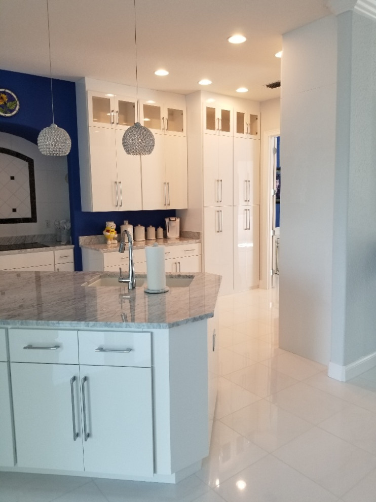 This is an example of a large modern single-wall eat-in kitchen in Orlando with flat-panel cabinets, white cabinets, marble benchtops and with island.