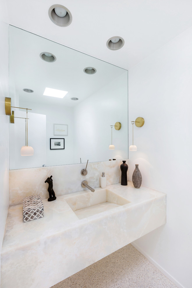 Midcentury powder room in Los Angeles with an integrated sink, white walls and onyx benchtops.