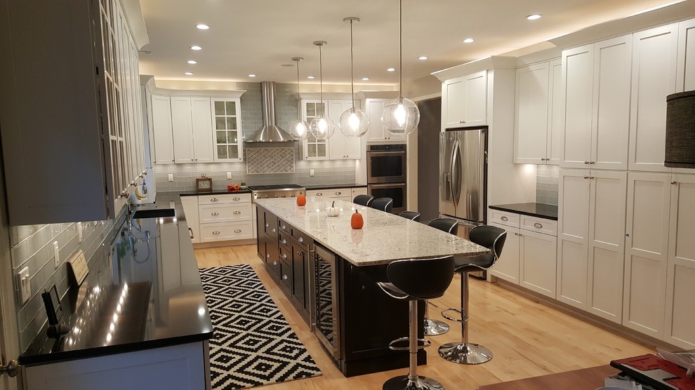 Eat-in kitchen - mid-sized transitional single-wall light wood floor and yellow floor eat-in kitchen idea with an undermount sink, shaker cabinets, white cabinets, quartz countertops, gray backsplash, glass tile backsplash, stainless steel appliances and an island