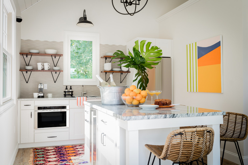 Inspiration for a small beach style single-wall separate kitchen in Boston with an undermount sink, shaker cabinets, white cabinets, granite benchtops, grey splashback, ceramic splashback, stainless steel appliances, vinyl floors, with island, brown floor and multi-coloured benchtop.