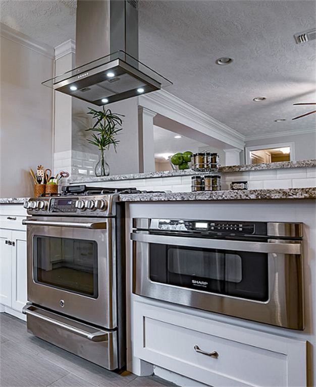 Photo of a mid-sized arts and crafts galley open plan kitchen in Houston with a single-bowl sink, shaker cabinets, white cabinets, granite benchtops, white splashback, subway tile splashback, stainless steel appliances, vinyl floors, no island and brown floor.