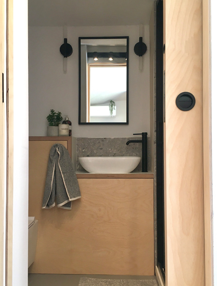 Aménagement d'une petite salle d'eau grise et noire en bois clair avec un placard à porte plane, une douche à l'italienne, WC suspendus, des carreaux de céramique, un mur blanc, un sol en linoléum, une vasque, un plan de toilette en stratifié, un sol gris, une cabine de douche à porte coulissante, un plan de toilette blanc, une niche, meuble simple vasque, meuble-lavabo sur pied et un plafond voûté.