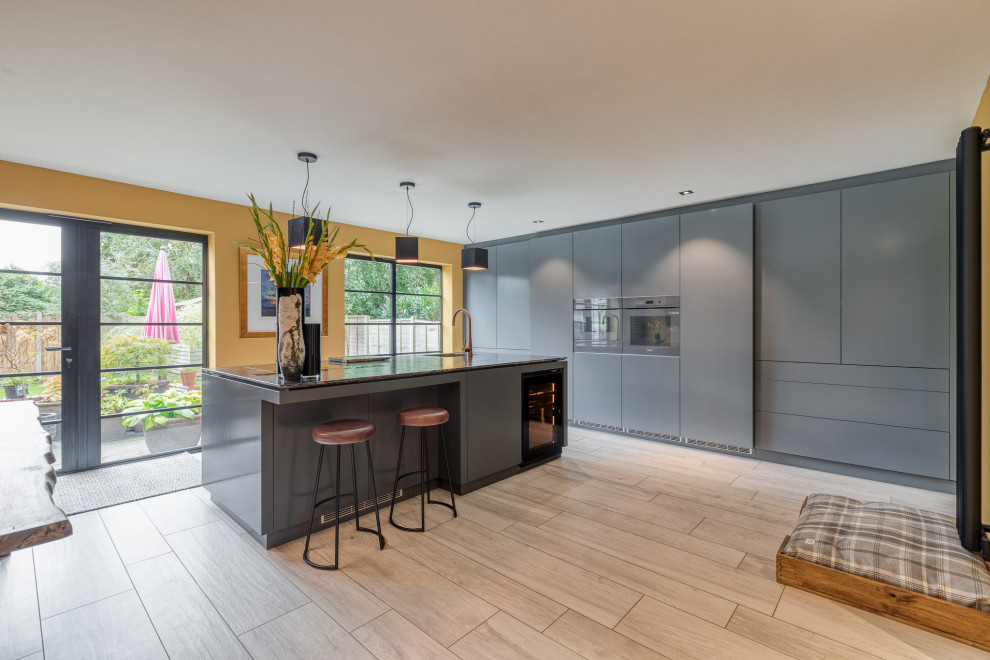 Inspiration for a large contemporary single-wall eat-in kitchen in Hertfordshire with a drop-in sink, flat-panel cabinets, grey cabinets, granite benchtops, panelled appliances, with island and brown benchtop.