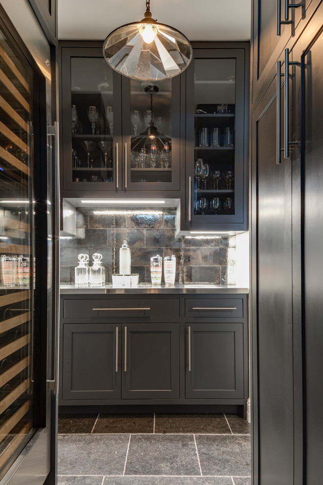 Inspiration for a mid-sized transitional home bar in Denver with grey cabinets, brown splashback, stainless steel benchtops, ceramic splashback, ceramic floors, grey floor, grey benchtop and shaker cabinets.