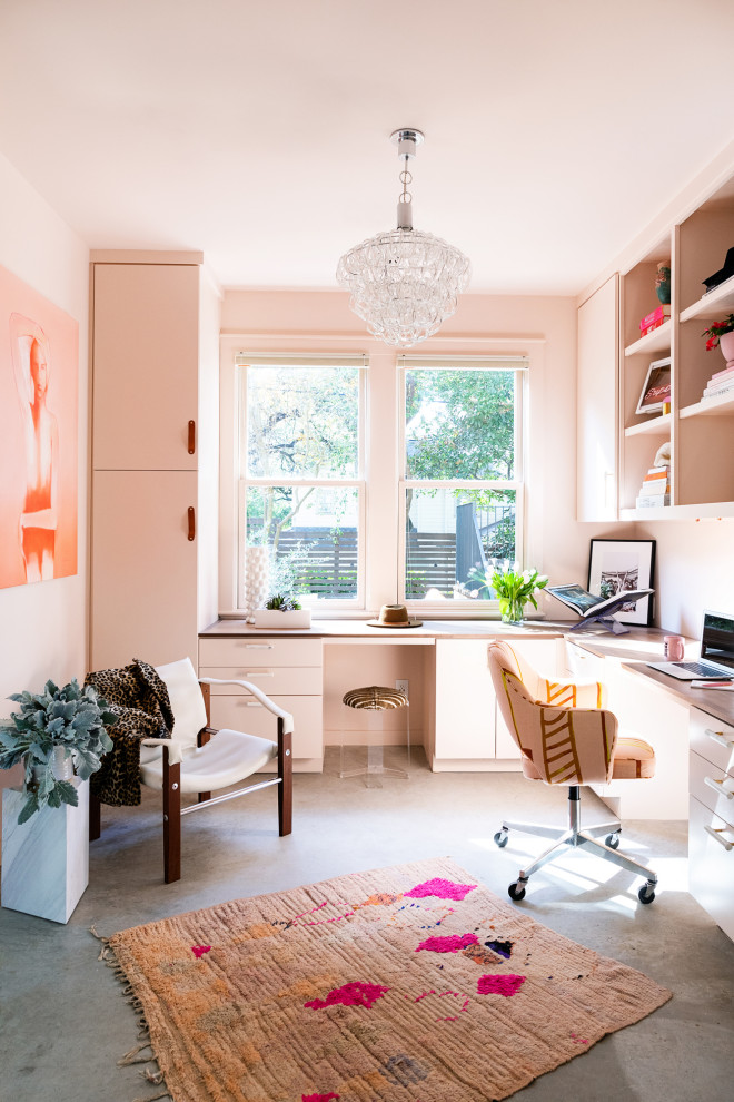 Inspiration for a contemporary home office in Austin with pink walls, concrete flooring, a built-in desk and grey floors.