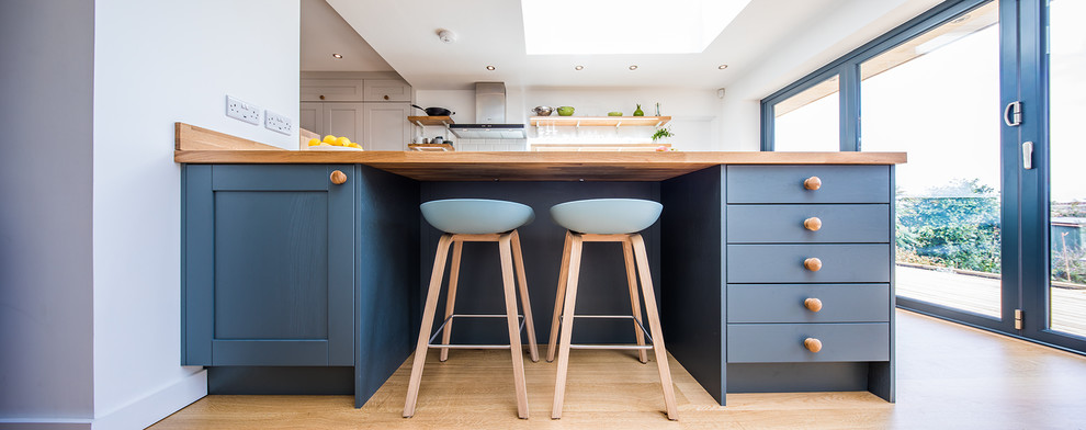 Design ideas for a large contemporary galley eat-in kitchen in Other with an integrated sink, shaker cabinets, grey cabinets, wood benchtops, white splashback, ceramic splashback, panelled appliances, medium hardwood floors, a peninsula and brown floor.