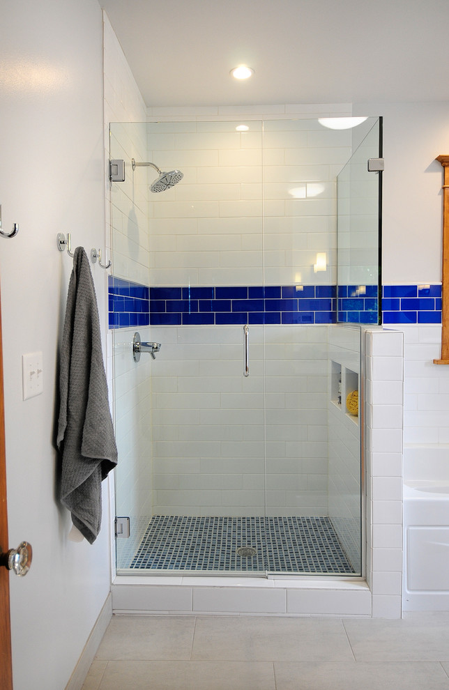 This is an example of a large transitional kids bathroom in Minneapolis with shaker cabinets, medium wood cabinets, an alcove tub, a corner shower, a two-piece toilet, blue tile, ceramic tile, grey walls, porcelain floors, an undermount sink, solid surface benchtops, beige floor and a hinged shower door.