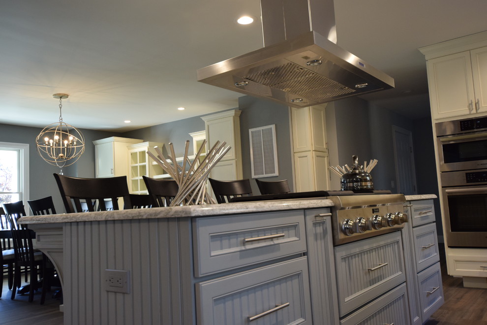 Open concept kitchen - large transitional medium tone wood floor open concept kitchen idea with an undermount sink, beaded inset cabinets, white cabinets, granite countertops, beige backsplash, ceramic backsplash, stainless steel appliances and an island