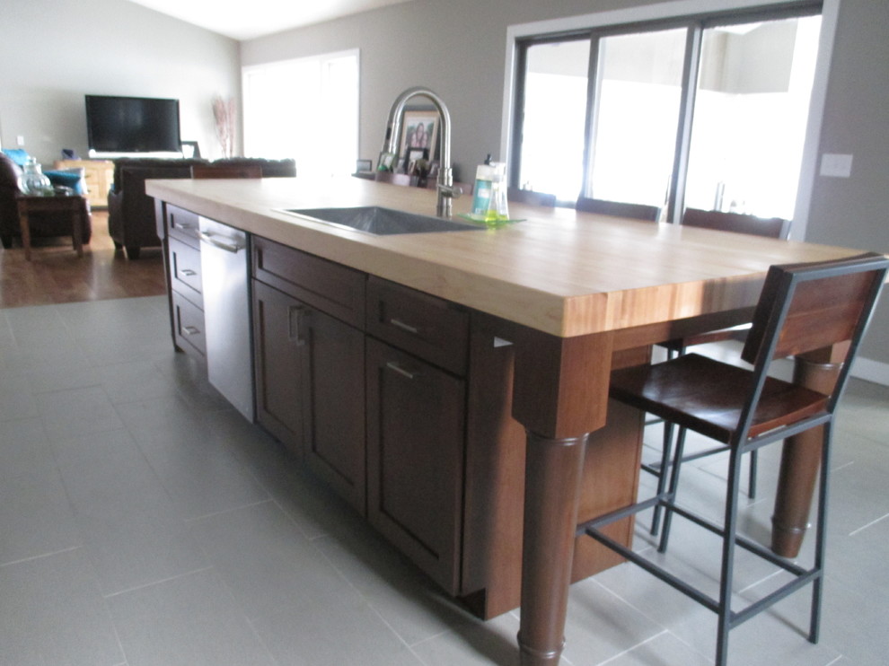 Inspiration for a transitional galley ceramic tile eat-in kitchen remodel with a drop-in sink, shaker cabinets, dark wood cabinets, wood countertops, multicolored backsplash, glass tile backsplash, stainless steel appliances and an island