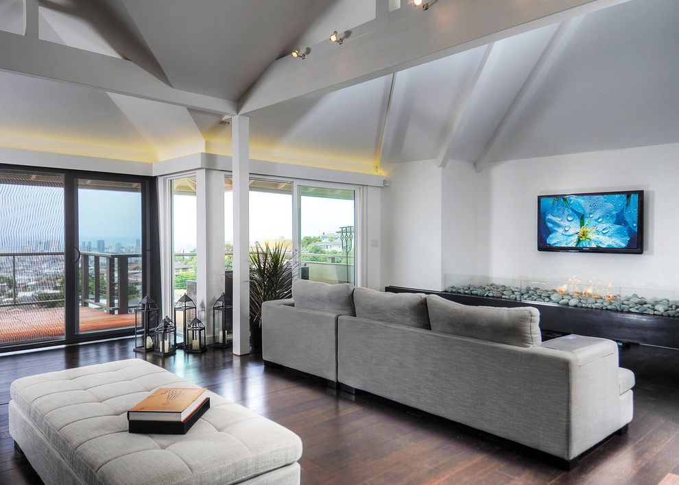 This is an example of a mid-sized contemporary open concept living room in Hawaii with white walls, bamboo floors, a wall-mounted tv, no fireplace and brown floor.