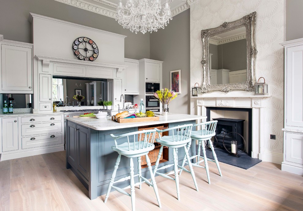Inspiration for an eclectic kitchen in Edinburgh with recessed-panel cabinets, white cabinets, mirror splashback, light hardwood floors and with island.