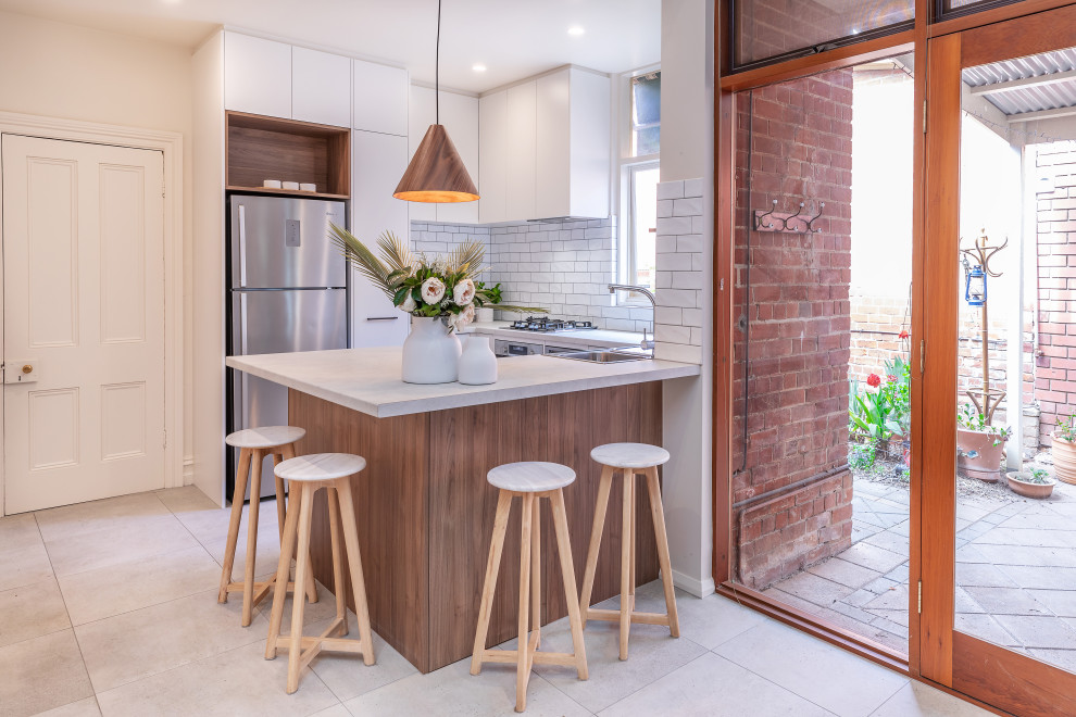 Small contemporary u-shaped kitchen in Adelaide with a double-bowl sink, flat-panel cabinets, white cabinets, laminate benchtops, white splashback, subway tile splashback, stainless steel appliances, cement tiles, a peninsula, grey floor and grey benchtop.