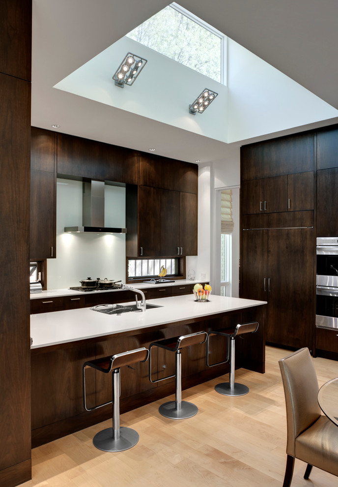 Photo of a contemporary kitchen in Dallas with flat-panel cabinets, dark wood cabinets and panelled appliances.
