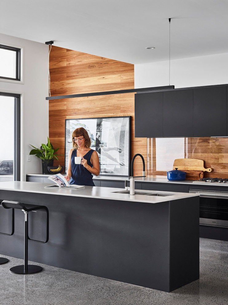 Inspiration for a mid-sized modern galley eat-in kitchen in Sunshine Coast with an undermount sink, black cabinets, concrete benchtops, timber splashback, stainless steel appliances, concrete floors, with island, green floor and white benchtop.
