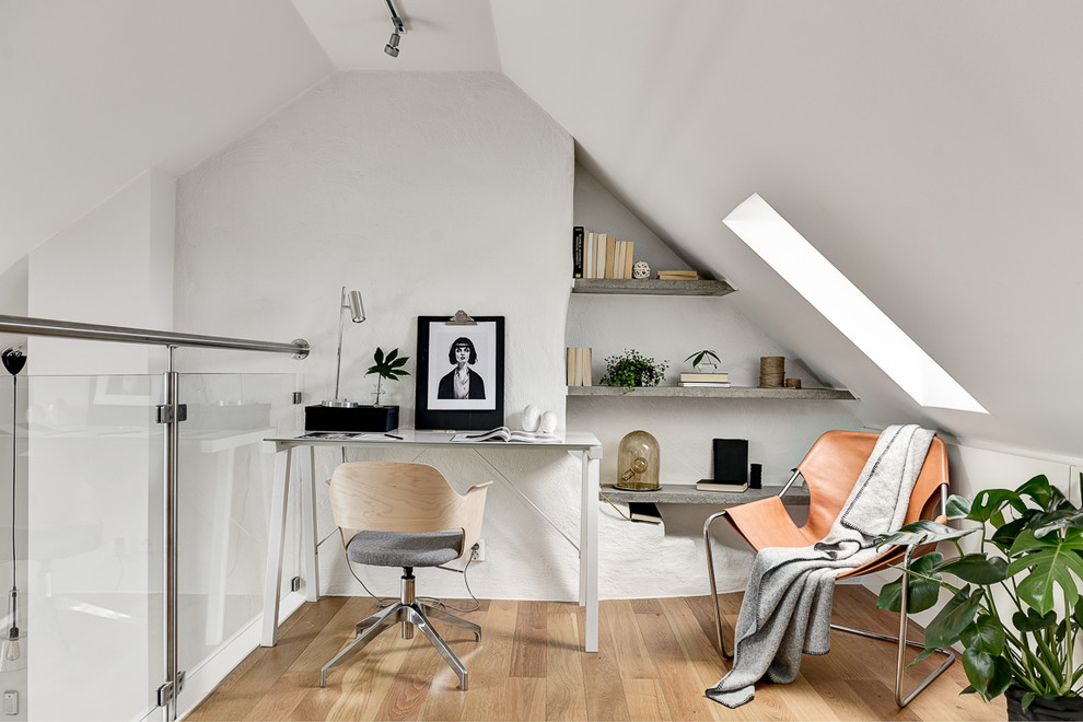This is an example of a mid-sized scandinavian home studio in Stockholm with white walls, light hardwood floors, no fireplace and a freestanding desk.