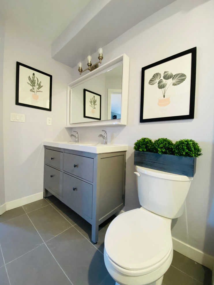 Aménagement d'une salle de bain contemporaine avec un placard à porte plane, des portes de placard grises, un mur gris, un sol en carrelage de porcelaine, un sol gris, un plan de toilette blanc, meuble double vasque et meuble-lavabo sur pied.