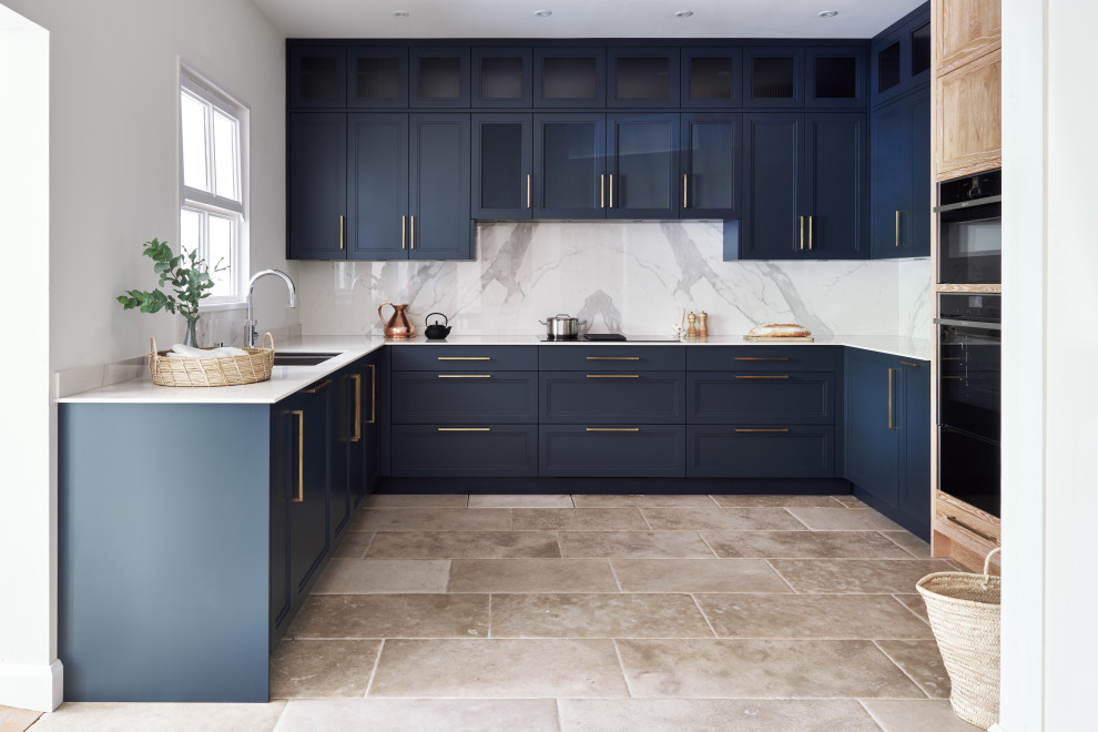 Design ideas for a transitional u-shaped kitchen in Wiltshire with an undermount sink, recessed-panel cabinets, blue cabinets, white splashback, stone slab splashback, stainless steel appliances, no island, beige floor and white benchtop.