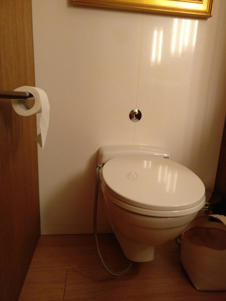 Photo of a small contemporary master bathroom in Milan with a wall-mount toilet, white tile, stone slab, white walls, bamboo floors and brown floor.