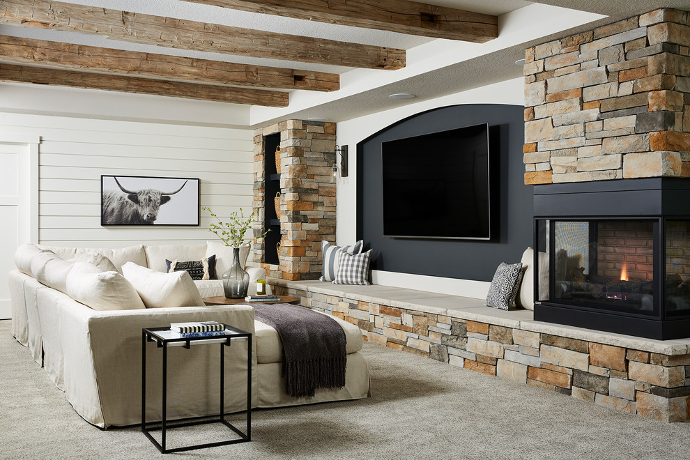 This is an example of a large country basement in Minneapolis with grey walls, carpet, a two-sided fireplace, a stone fireplace surround and grey floor.