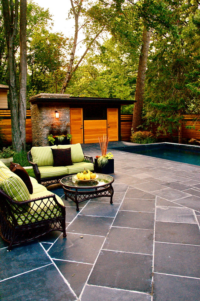 Inspiration for a large contemporary backyard patio in Toronto with a water feature, natural stone pavers and a roof extension.
