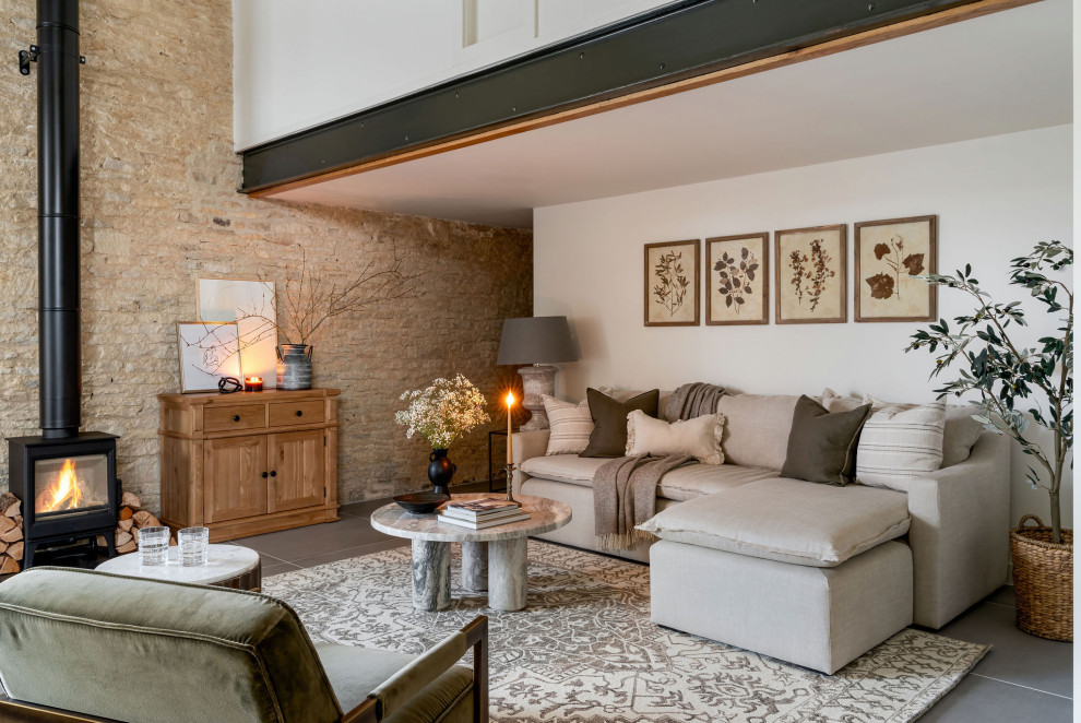 This is an example of a large farmhouse open plan living room in Wiltshire with a wood burning stove, a vaulted ceiling, beige walls and grey floors.