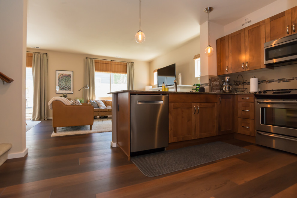 Small midcentury l-shaped open plan kitchen in Seattle with stainless steel appliances, vinyl floors, red floor, shaker cabinets, medium wood cabinets, granite benchtops, beige splashback, matchstick tile splashback, a peninsula and grey benchtop.