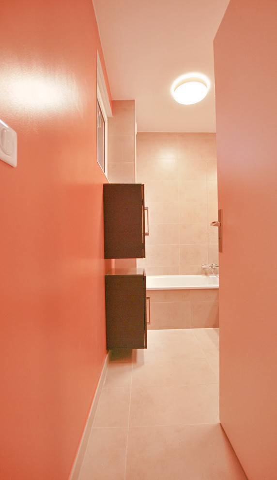 Photo of a small contemporary kids bathroom with flat-panel cabinets, dark wood cabinets, a drop-in tub, a shower/bathtub combo, orange walls, ceramic floors, beige floor, a hinged shower door, beige tile, ceramic tile, an integrated sink, a single vanity and a floating vanity.
