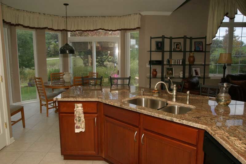 Kitchen pantry - transitional u-shaped medium tone wood floor kitchen pantry idea in Chicago with raised-panel cabinets, medium tone wood cabinets and granite countertops