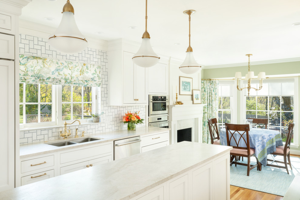 Diseño de cocina clásica renovada con puertas de armario blancas, salpicadero blanco, salpicadero de azulejos de cerámica, electrodomésticos de acero inoxidable, una isla y encimeras blancas