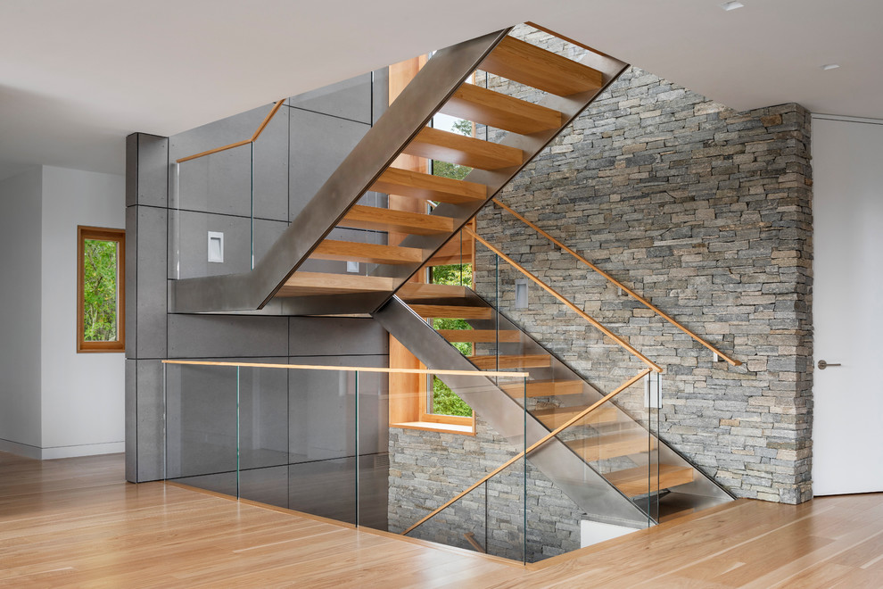 This is an example of a mid-sized modern wood u-shaped staircase in Providence with open risers and glass railing.