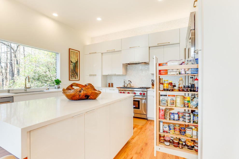 This is an example of a large modern u-shaped eat-in kitchen in Birmingham with an undermount sink, flat-panel cabinets, white cabinets, quartz benchtops, white splashback, porcelain splashback, stainless steel appliances, medium hardwood floors, with island and white benchtop.