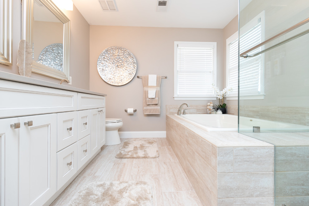 This is an example of a mid-sized transitional master bathroom in Other with shaker cabinets, white cabinets, a hot tub, a corner shower, a one-piece toilet, white tile, porcelain tile, beige walls, porcelain floors, an undermount sink and engineered quartz benchtops.