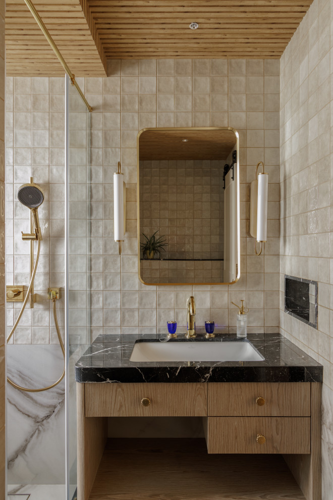 Transitional bathroom in Mumbai With Flat-panel Cabinets, Medium Wood Cabinets, an Alcove Shower, Beige Tile and an Undermount Sink.