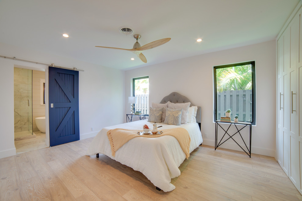 Country master bedroom in Miami with white walls, light hardwood floors and beige floor.