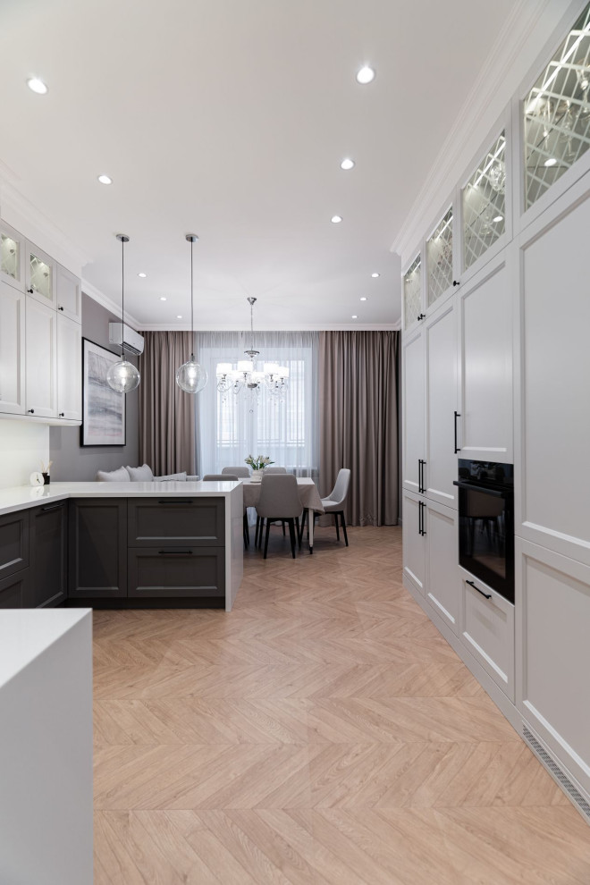 Photo of a mid-sized transitional u-shaped eat-in kitchen in Other with glass-front cabinets, white cabinets, solid surface benchtops, white splashback, white appliances and white benchtop.