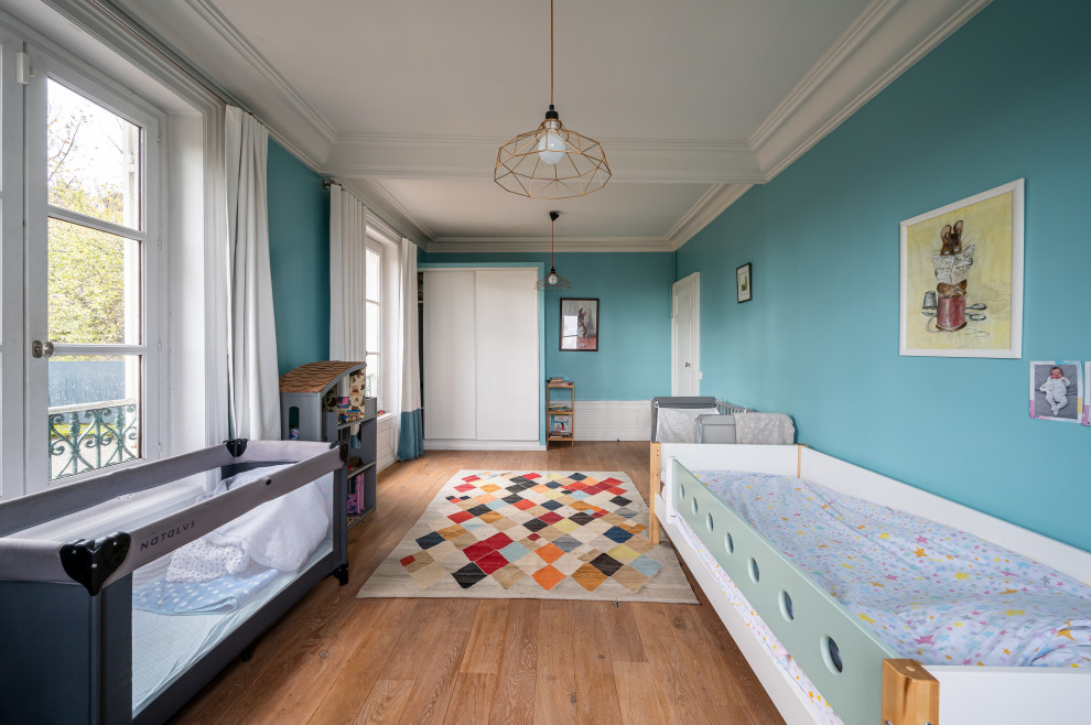 Foto de dormitorio infantil de 1 a 3 años contemporáneo grande con paredes azules, suelo de madera clara, suelo marrón y vigas vistas