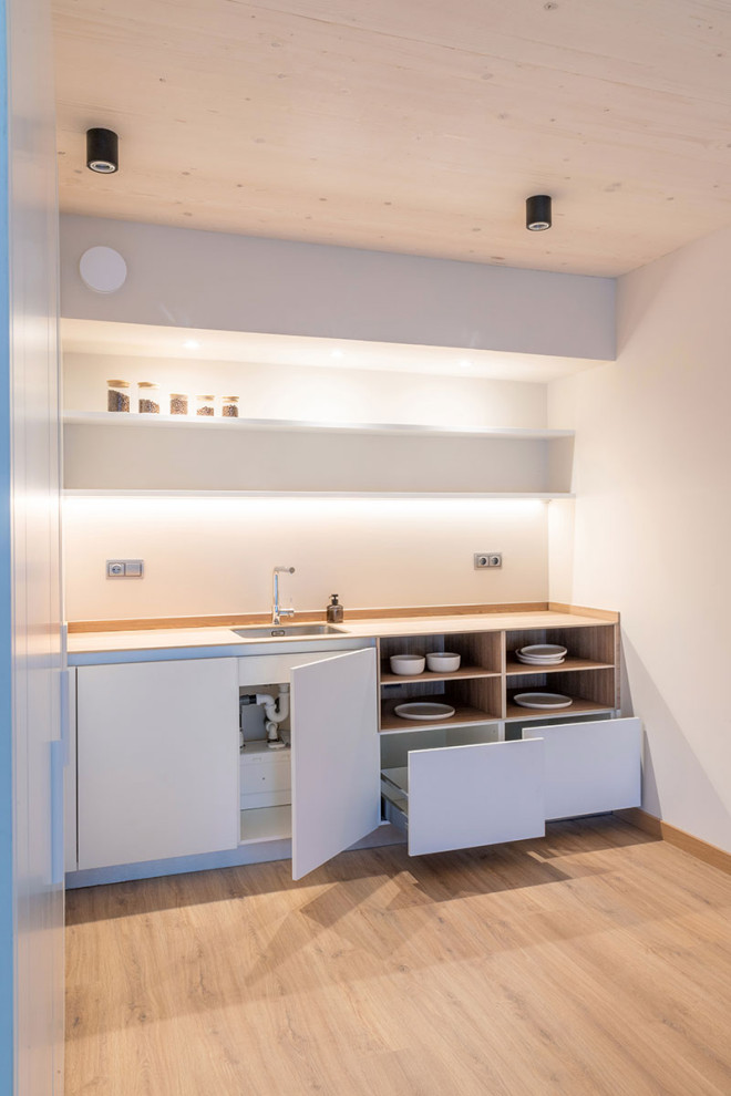 Foto di una cucina minimalista con ante lisce, ante grigie, pavimento in legno massello medio, penisola e pavimento marrone