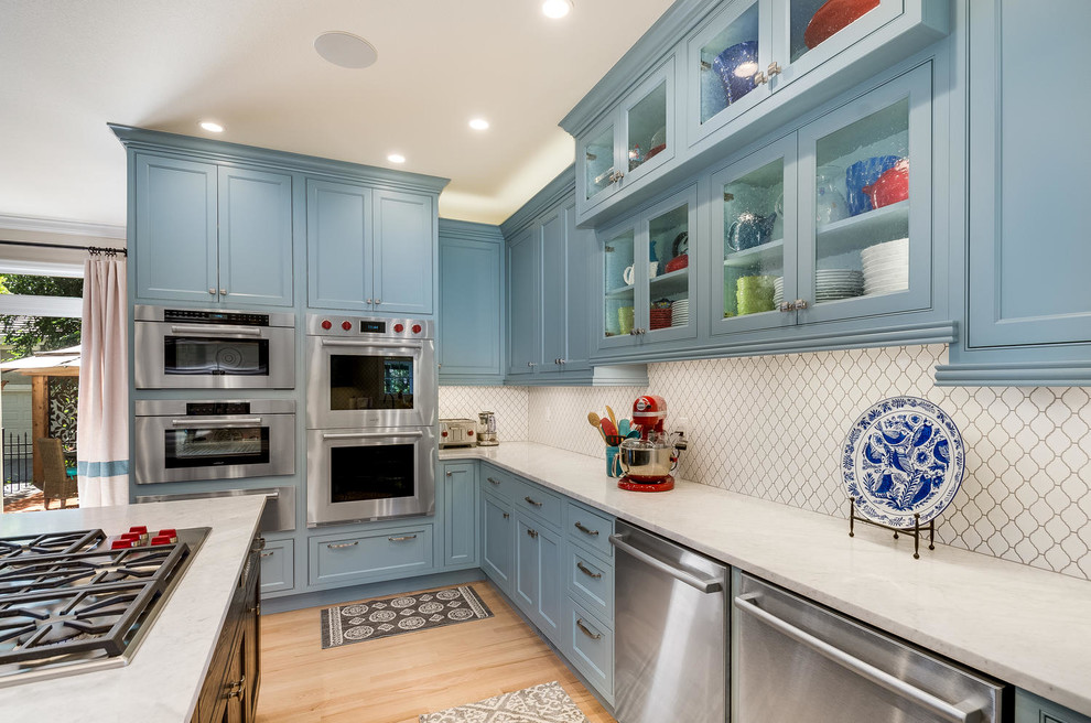 Photo of a transitional kitchen in Denver with beaded inset cabinets, blue cabinets, white splashback, stainless steel appliances, medium hardwood floors, with island and brown floor.