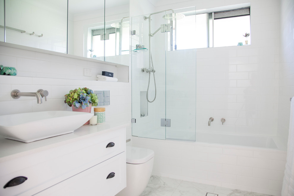 Inspiration for a mid-sized contemporary master bathroom in Sydney with shaker cabinets, white cabinets, a drop-in tub, a shower/bathtub combo, a wall-mount toilet, white tile, subway tile, white walls, porcelain floors, a vessel sink and engineered quartz benchtops.
